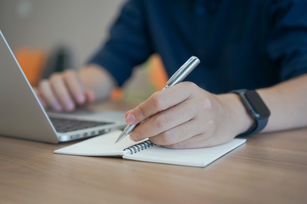 strony biznesmen pisania treści lub coś na notebooka za pomocą laptopa w domu biura