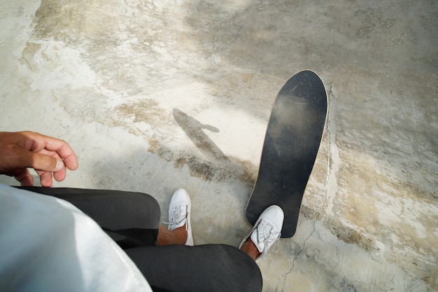 Strzał POV. Nogi na deskorolce longboard w skateparku z betonem.