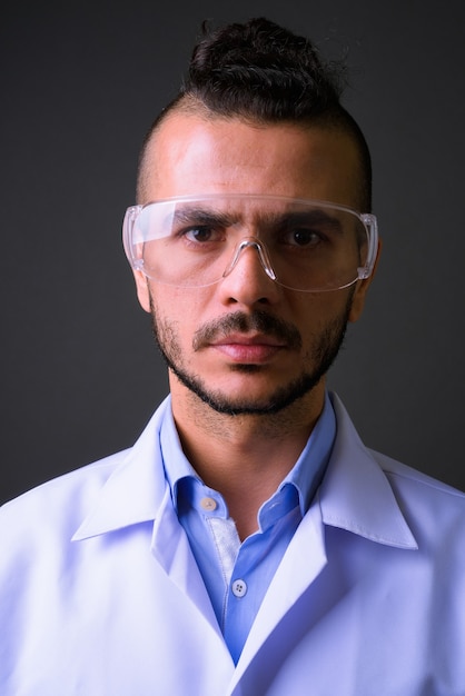 Strzał studio przystojny lekarz turecki mężczyzna w okularach ochronnych na szarym tle