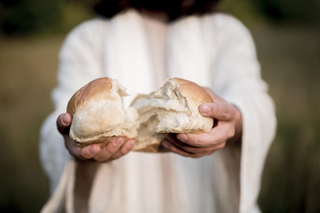 Strzał zbliżenie Jezusa Chrystusa dzieląc chleb z niewyraźnym tłem