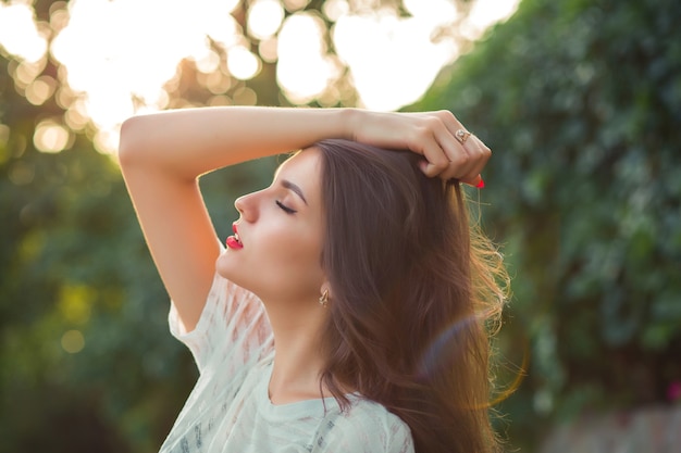 Strzał zbliżenie wspaniała brunetka kobieta z czerwonymi ustami pozowanie z zamkniętymi oczami