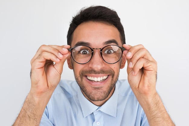 Strzał zbliżenie zdumiony młody europejski przystojny mężczyzna patrząc przez okrągłe okulary dotyka obręczy okularów uśmiechając się zdrowy uśmiech toothy pozowanie w studio Ludzie emocji i koncepcji stylu życia