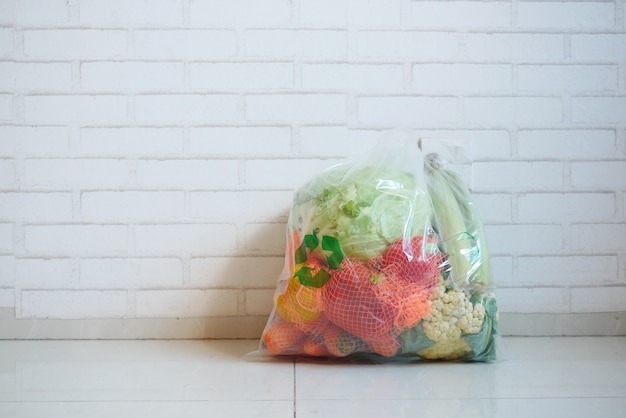 Strzałki z recyklingu znakują na torbie na zakupy z warzywami na podłodze