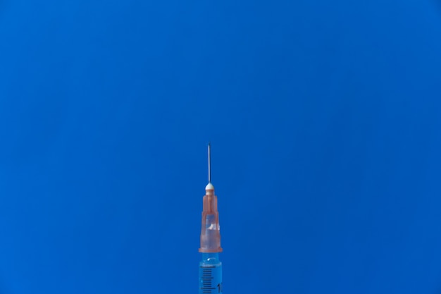 Strzykawka umieszczona na niebieskim tle. Koncepcja szczepień
