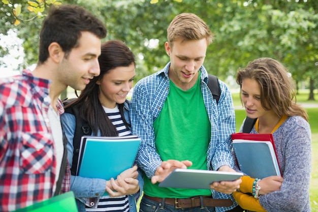 Zdjęcie studenci collegu z torbami i książkami używać pastylka peceta w parku