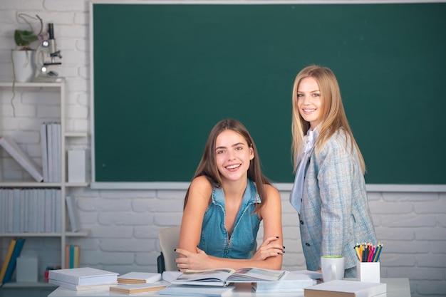 Studenci dziewcząt przyjaciół w klasie na uczelni lub na uniwersytecie na tle tablicy