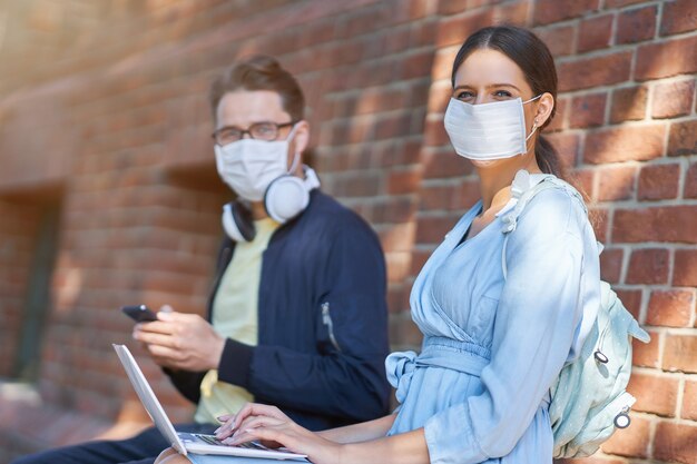 Studenci spędzający czas na terenie kampusu noszący maski ochronne i utrzymujący dystans z powodu pandemii koronawirusa