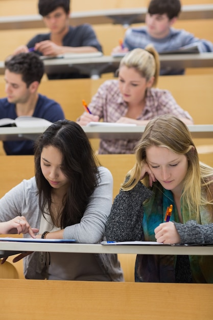 Studenci uczący się w sali wykładowej z jedną dziewczyną przy użyciu komputera typu tablet