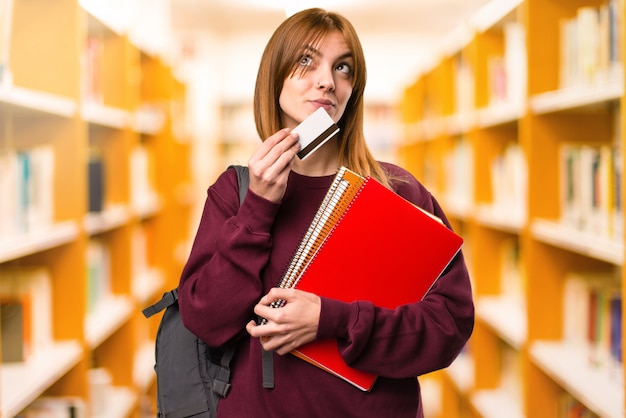 Studencka kobieta trzyma kredytową kartę na unfocused tle. powrót do szkoły