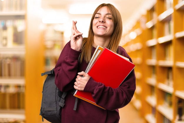 Studencka kobieta z jej palcami krzyżuje na unfocused tle. powrót do szkoły