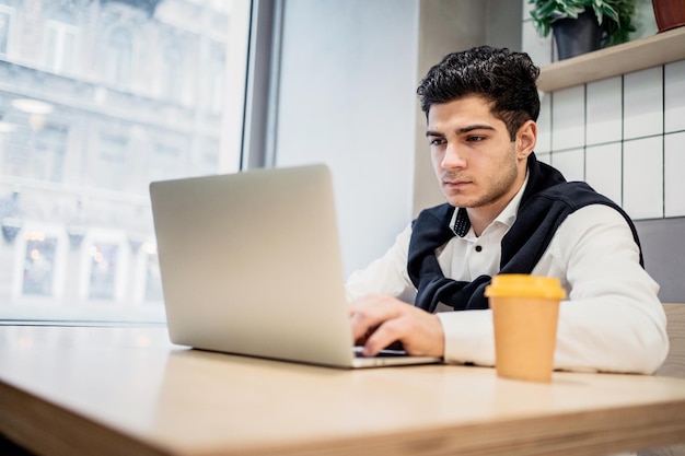 Student brunetka pracujący online na laptopie w kawiarni-restauracji