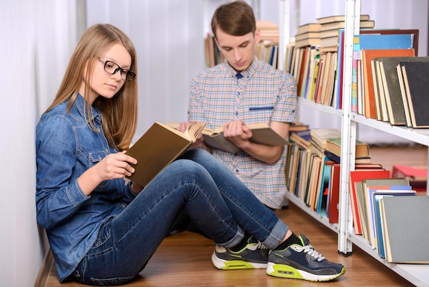 Zdjęcie student czyta książkę i korzysta z laptopa w bibliotece