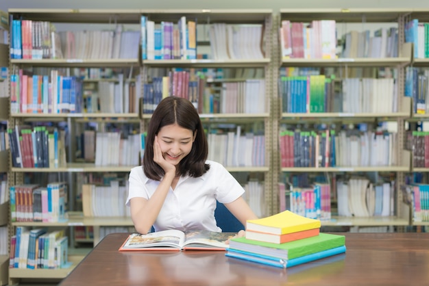 student czytanie książki w bibliotece na uniwersytecie.