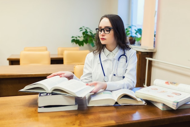 Student medycyny dla podręczników. Gabinet chirurgii pięknej dziewczyny w bibliotece. Pielęgniarka