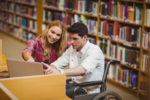 Student na wózku inwalidzkim pracujący z kolegą z klasy w bibliotece