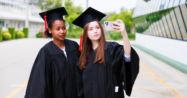 Student noszący suknię i robiący zdjęcie przez smartfona kończący szkołę Szczęśliwego sukcesu absolwenta i świętowania Gratulacje