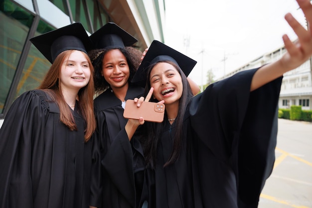 Student noszący suknię i robiący zdjęcie przez smartfona kończący szkołę Szczęśliwego sukcesu absolwenta i świętowania Gratulacje