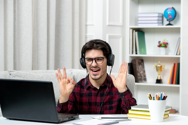 Student online młody facet w kraciastej koszuli w okularach studiuje na komputerze machając rękami