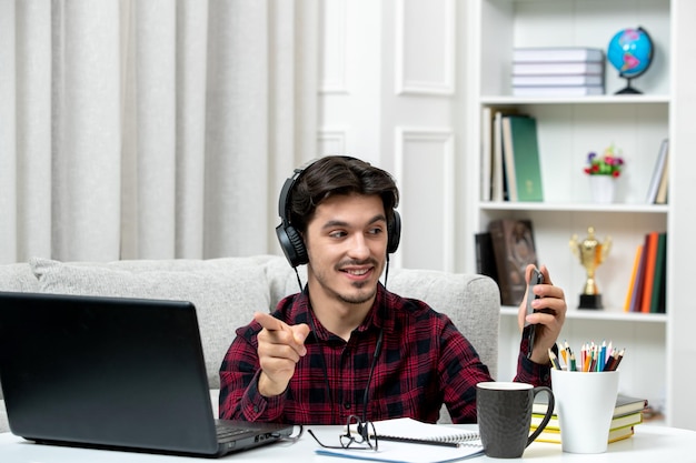 Student online słodki facet w kraciastej koszuli i okularach studiujący na komputerze robiący selfie