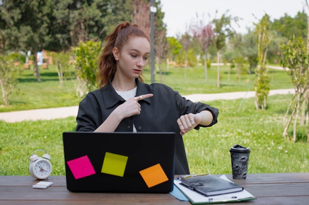 Student-programista-freelancer pracujący przy laptopie, patrzący w dół, pokazujący