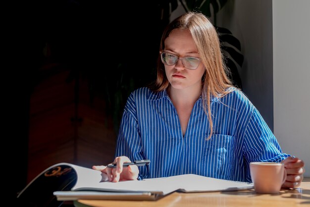 Student przygotowujący się do egzaminu na uniwersytecie w kawiarni z programem nauczania zeszytu na filiżankę kawy i podr...