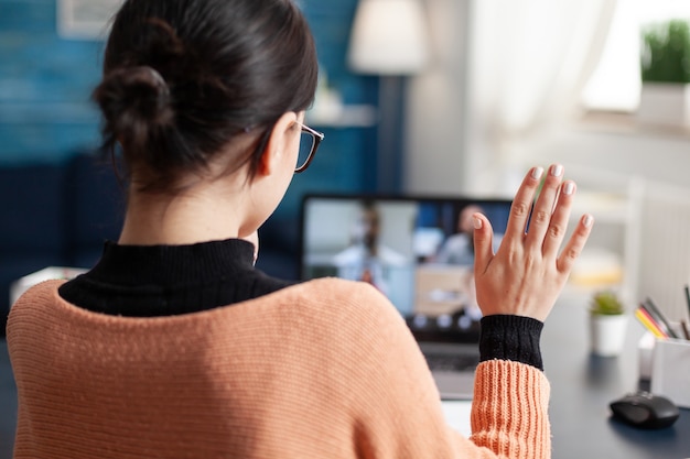 Student Rozmawiający Z Kolegą Z Uniwersytetu Podczas Internetowego Seminarium Internetowego Przy Użyciu Komputera Przenośnego, Młoda Kobieta Prowadząca Zdalną Edukację Podczas Kwarantanny Koronawirusa, Siedząc W Salonie