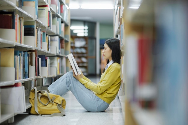Student siedzi na podłodze i czyta w bibliotece