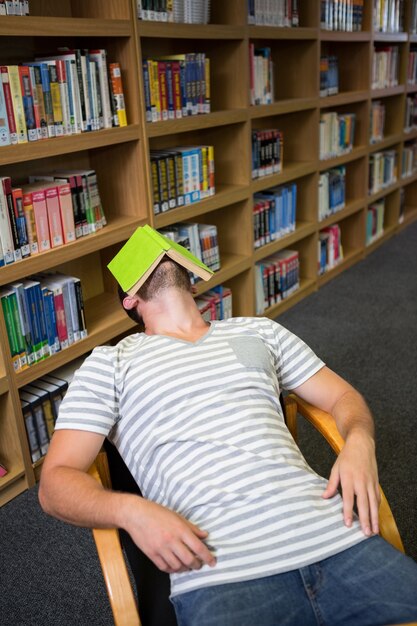 Student śpi W Bibliotece Z Książką Na Twarzy