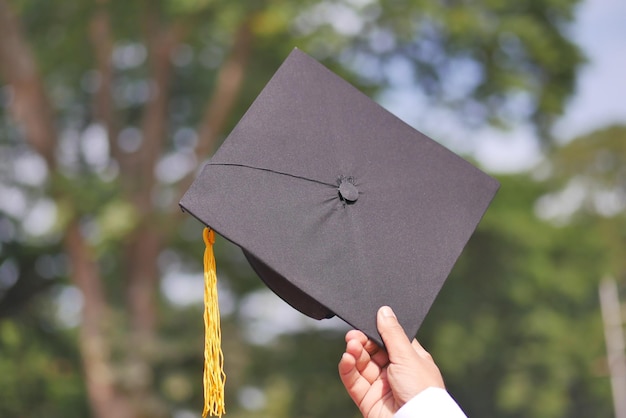 Student trzyma kapelusze w ręku podczas sukcesu na żółtym tle