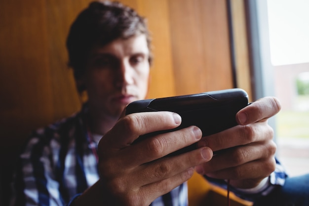 Student używa telefonu komórkowego w pobliżu okna