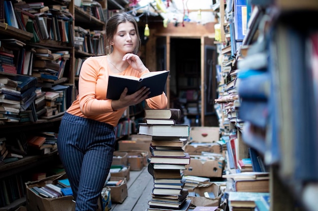 Studentka czyta książkę w bibliotece, kobieta lubi dużo czytać, szuka literatury