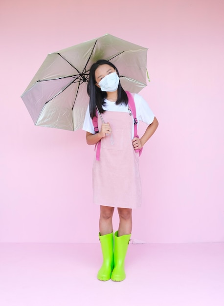 Studentka młoda dziewczyna nosi maskę z parasolem na różowym tle