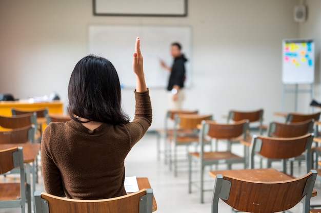 Studentka podnosi ręce i pyta nauczycieli w klasie uniwersyteckiej