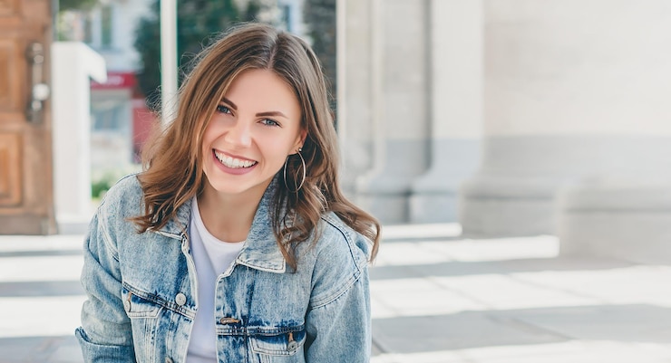 Zdjęcie studentka siedzi na tle uniwersytetu i uśmiecha się śliczna młoda kobieta śmieje się patrząc na kamerę web banner copy space