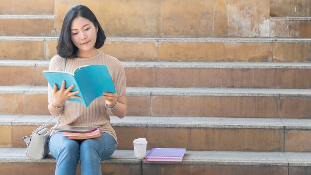 studentka teen girl z książką edukacji i filiżanka kawy siedzieć na schodach pieszych