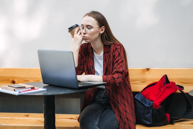 Studentka ucząca się trudnego egzaminu i śpiąca na książkach w ulicznej kawiarni zmęczona dziewczyna pracująca