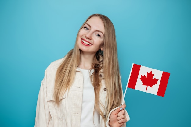 studentka uśmiechnięta z małą flagą Kanady i patrząc na kamery