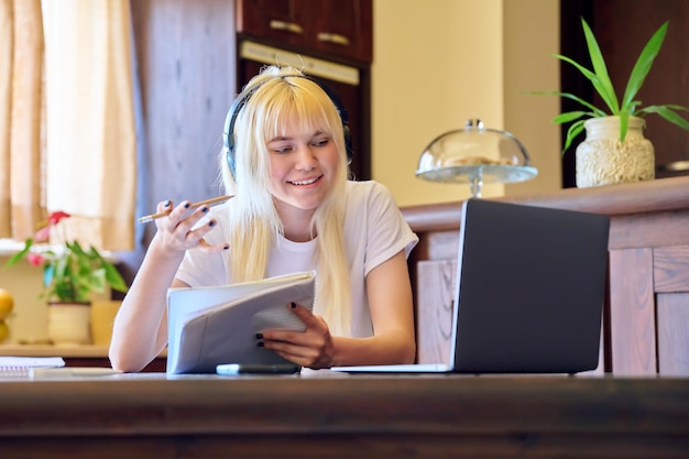 Studentka w słuchawkach, korzystająca z laptopa, ucząca się w domu