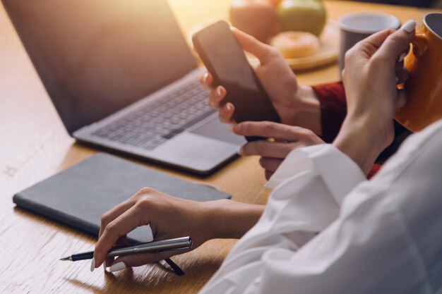 Studentki zauważają z książek w bibliotece azjatyckiej dziewczyny siedzącej na kanapie za pomocą laptopa i tabletu do wyszukiwania informacji online w salonie