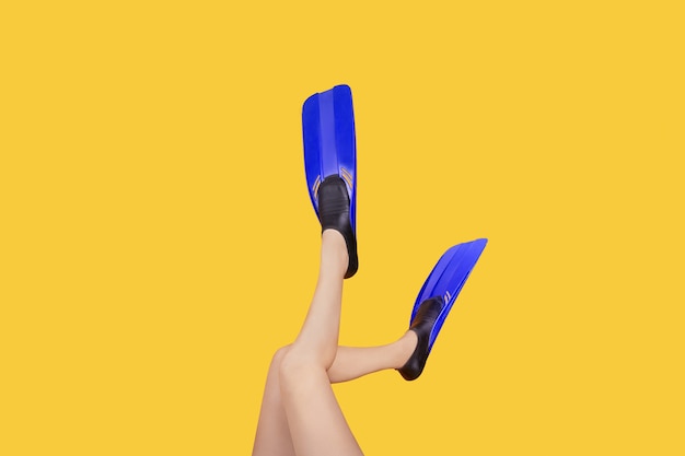 Studio fotografii kobiecych nóg w płetwach na żółtym tle, koncepcja letnich wakacji na morzu