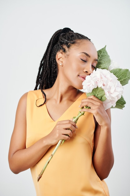 Studio portret atrakcyjnej młodej kobiety Murzynki, ciesząc się świeżym zapachem kwitnącego kwiatu hortensji