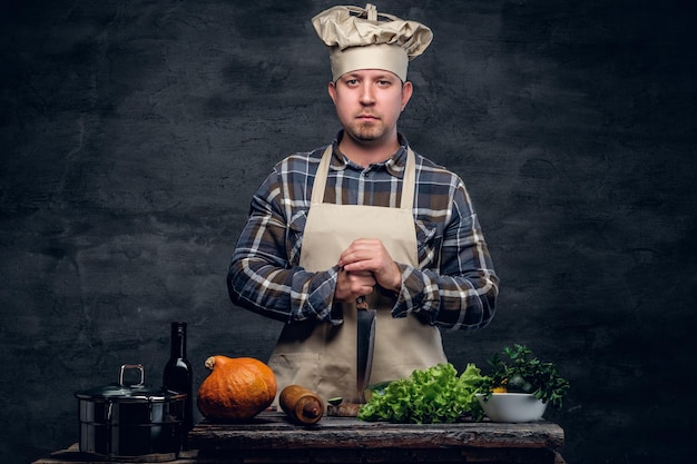 Studio portret kucharza przygotowującego sałatkę na ciemnym tle.