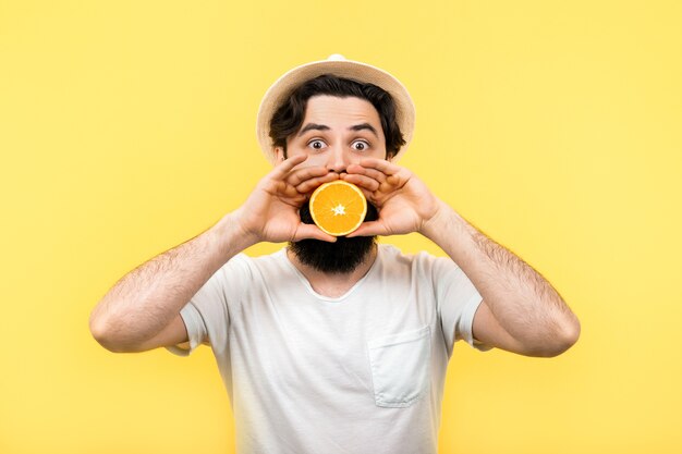 Studio portret zaskoczony brodaty mężczyzna trzyma w rękach pół pomarańczy cytrusowych