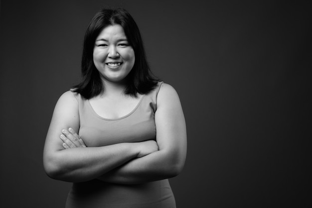 Studio strzałów pięknej nadwagą Azji kobieta ubrana bez rękawów sukienka na szarym tle w czerni i bieli
