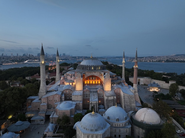 Stworzenie orbitującego zdjęcia drona lotniczego Świętego Wielkiego Meczetu Hagia Sophia z mostem Bosforu i panoramą miasta z flagą na tle w Fatih w Stambule w Turcji o zachodzie słońca