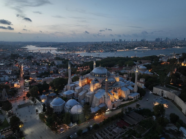 Stworzenie orbitującego zdjęcia drona lotniczego Świętego Wielkiego Meczetu Hagia Sophia z mostem Bosforu i panoramą miasta z flagą na tle w Fatih w Stambule w Turcji o zachodzie słońca