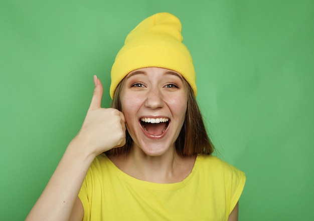 Zdjęcie styl życia, emocje i koncepcja ludzi szczęśliwa kobieta ubrana w żółte ubrania, dając kciuk w górę