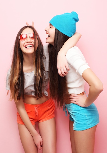 Styl życia ludzie nastolatki i koncepcja przyjaźni szczęśliwi uśmiechnięci ładne nastoletnie dziewczyny lub przyjaciele przytulający się na różowym tle