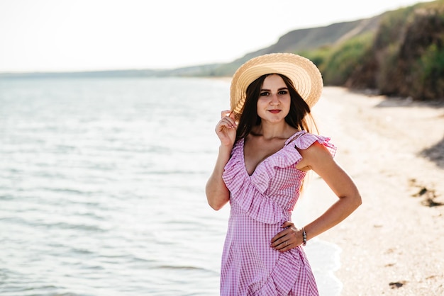 Styl życia Obraz beztroskiej podróżującej uśmiechniętej kobiety w białej bluzce i słomkowym kapeluszu spędzającej wolny czas na plaży Letni nastrój
