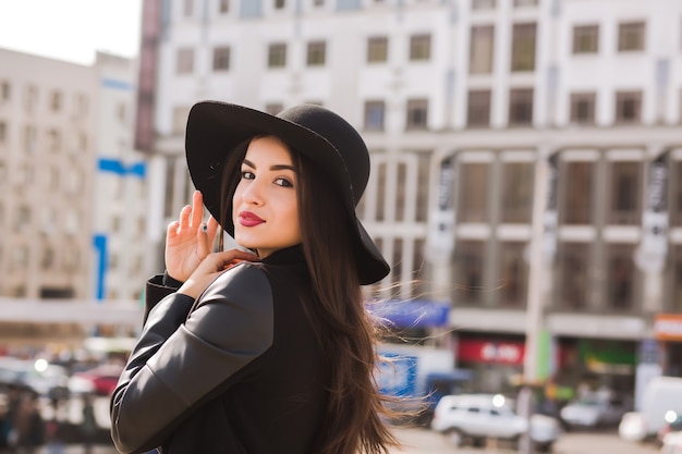 Styl życia portret ładna brunetka modelka w modnym płaszczu i kapeluszu pozowanie na ulicy miasta